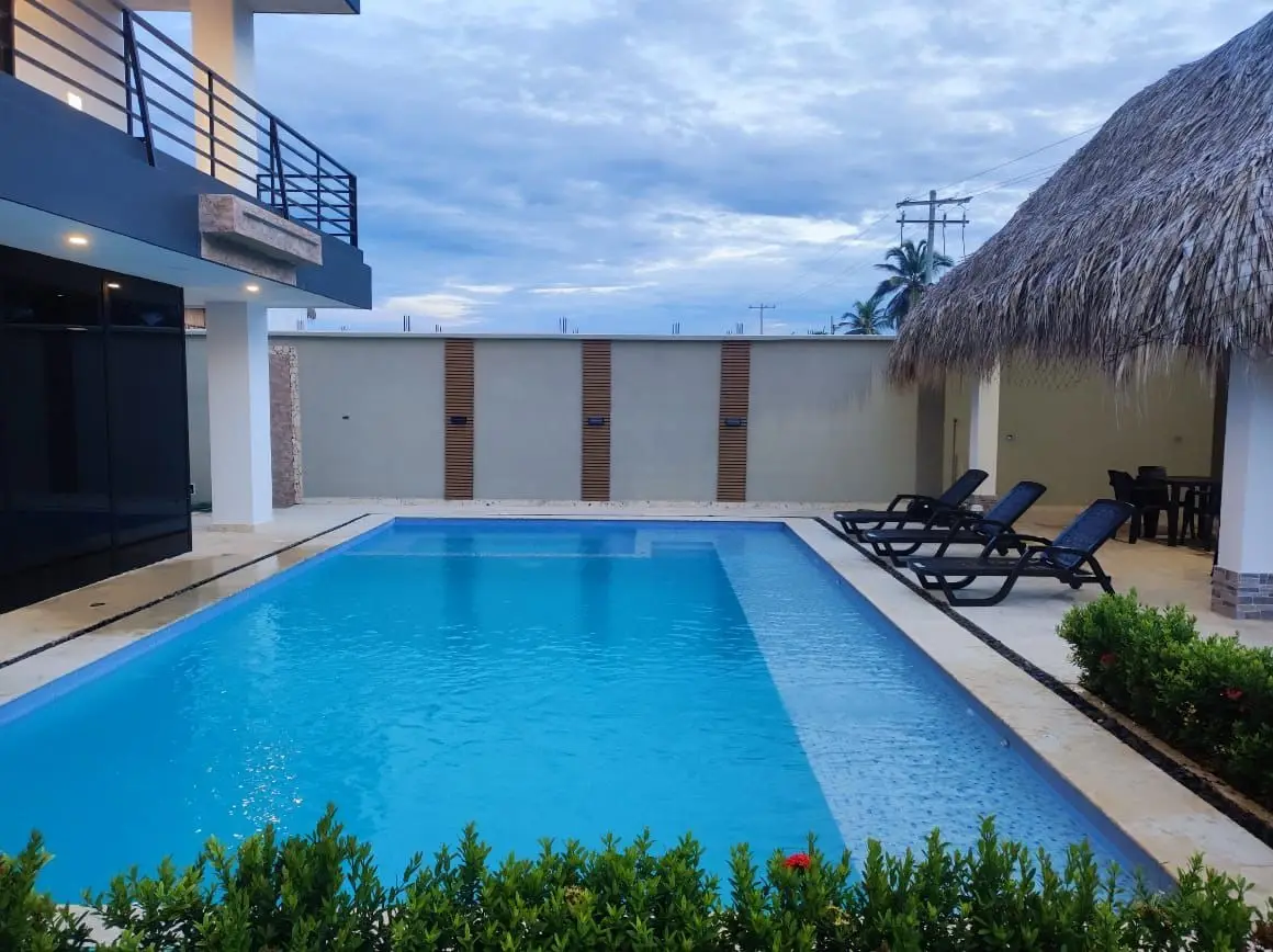 Piscina privada vista desde el balcón, con camas de sol y kiosco de palma